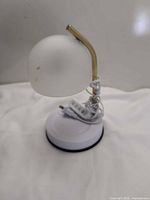 Side view of lamp showing frosted shade, gold stem, white base, cord and inline dimmer
