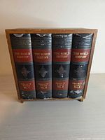 Front view of closed wooden faux-book box showing spine graphics and scuffs