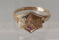 Front view of gold ring showing monogram and pink gemstone