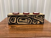Front view of wood candle holder showing indigenous motif and three tealight candles