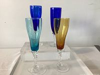 Four colored Murano champagne goblets with twisted stems on display block