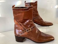 Side view of both brown leather boots showing strap and buckle