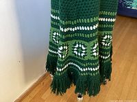Full view of green crochet skirt with white patterns and fringe