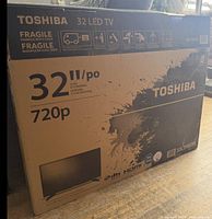 Front of factory box showing Toshiba branding, 32" size, 720p spec