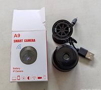 Front of box beside camera, mount, USB cable