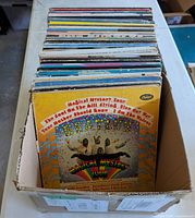 Box containing a stack of roughly sixty LP records, front album visible