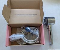 Open box showing shower head, hose, bracket, hardware