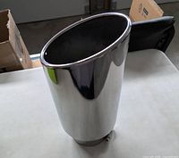 Side view of polished chrome exhaust tip showing oval outlet and reflective finish