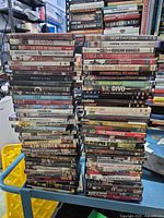 Three tall stacks of assorted DVD cases visible on table
