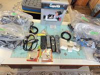 Full lot overview with remotes, CopyKit box, cables in bags, power taps and card adapters displayed