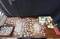 Overview of table showing loose stamps, tray of stamps, rows of matchbooks, coins