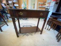 Front view showing drawer with brass pulls and lower shelf