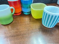 Five Holt-Howard mugs in assorted colors and shapes on tabletop