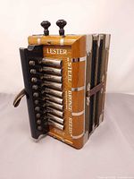 Full view of accordion showing wooden casing, button row, straps, graphics