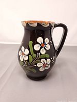 Front view of black glazed pottery jug with floral decoration