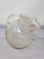 Side view showing ribbed spherical body, handle, and spout