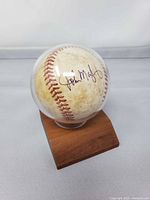 Autographed baseball in display case on wooden base