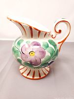 Full view of pitcher showing shape, floral decoration, and stripe detailing