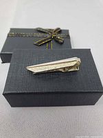 Front view of gold-tone tie clip on gift box