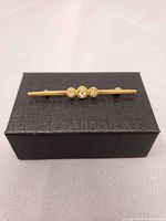 Front view of brooch resting on gift box showing full design