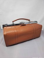 Front view of brown leather doctor’s bag showing chrome frame and handle