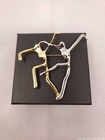 Front view of two-tone abstract dancer brooch on gift box