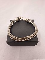 Full view of braided silver-tone bracelet on box