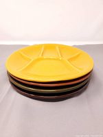 stack of four divided plates showing yellow top piece