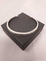 Full view of silver rhinestone open bangle on box
