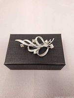 Front view of silver-tone floral rhinestone brooch on black box