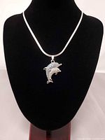 Full view of necklace displayed on bust showing chain and dolphin pendant