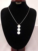 Full view of silver serpentine chain necklace displayed on bust showing triple mother-of-pearl pendant