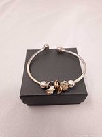 Full view of sterling silver open cuff bracelet with charms on box