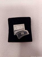 Front view of sterling silver CIBC 1B milestone pin on display pad