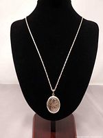 Full view of sterling silver rope chain with locket on display bust