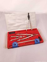 Open vinyl case showing full five-piece compass set and accessories in red insert