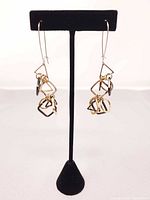 Full view of tri-coloured dangling earrings on stand