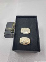 front view of cufflinks in box showing face design