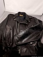 Full view of front and sleeve of black leather biker jacket