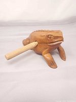 Side view of carved wooden frog with striker inserted