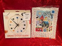 Front view of both sealed kits: Kikkerland Cross Stitch Clock box and RTO Snow Falling kit package
