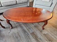 Oval mahogany finish coffee table showing top surface and cabriole legs