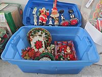 Overall view of open blue bin with assorted Christmas decorations