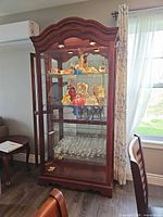 Full view of cherry mahogany curio cabinet with contents for scale