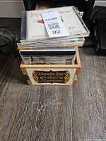 Stack of CDs in wooden crate with label on floor