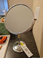 Front view of chrome and brass tabletop vanity mirror