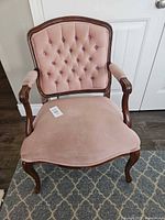 Full view of pink velvet armchair with wood frame