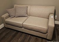 Front view of gray sofa with two seat cushions and two throw pillows