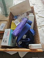 Overview of basket with assorted items inside including camera box, cervical collar, tubing, straps, bottle