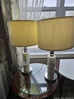 Both lamps on glass side table showing shades and bases